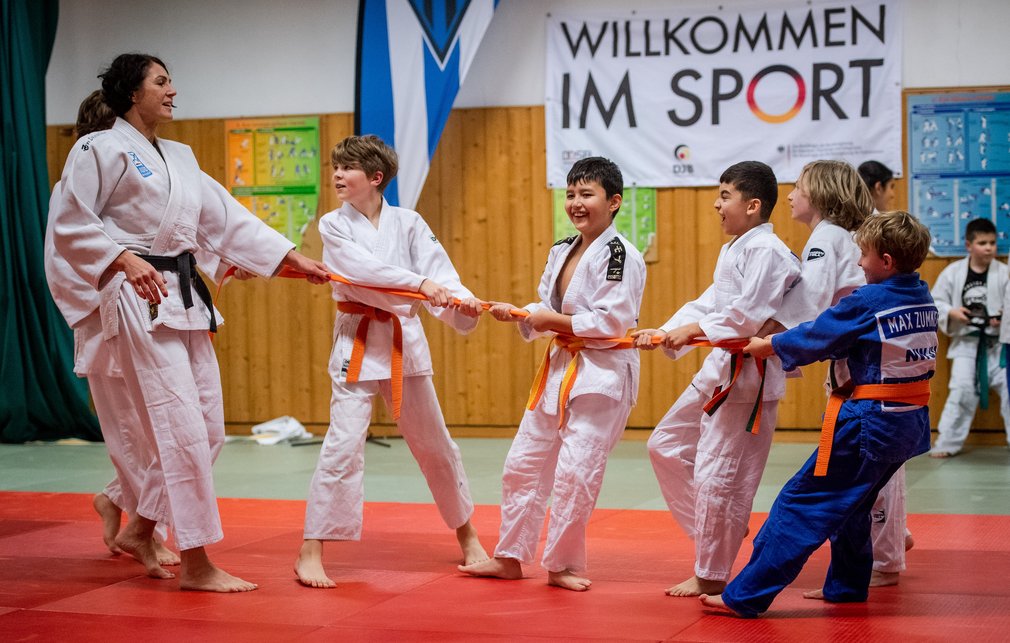 Kinder spielen mit einem Judoguertel Tauziehen.