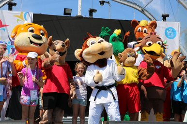 Das Maskottchen Yoko steht gemeinsam mit anderen Maskottchen auf einer Buehne.