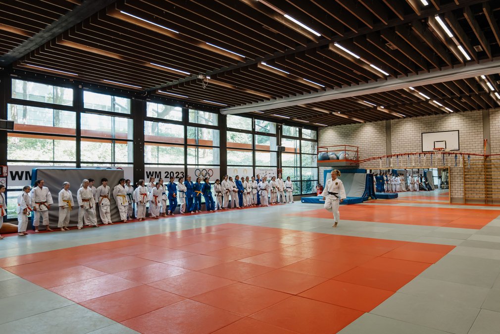 Maedchen beim Training im Ippon Girls Camp. Eine Judoka zeigt etwas und alle anderen schauen ihr zu.