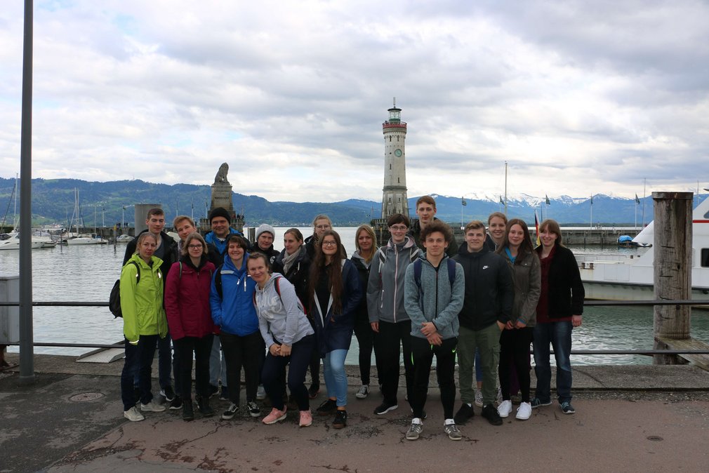 Eine Gruppe junger Personen posiert fuer ein Gruppenfoto in Lindau vor dem Bodensee.
