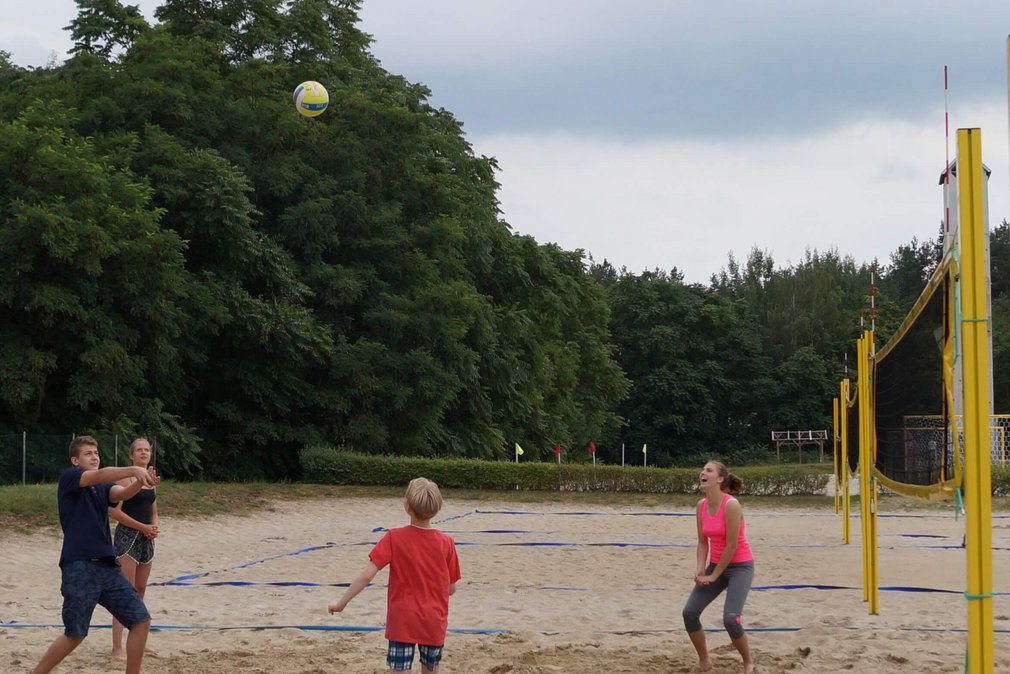 Vier Personen spielen Beachvolleyball.