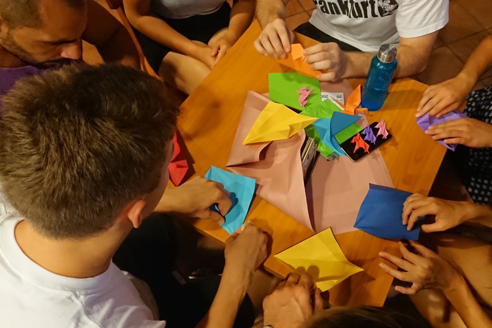 Eine Gruppe von Menschen bastelt Origami-Figuren mit Papier.