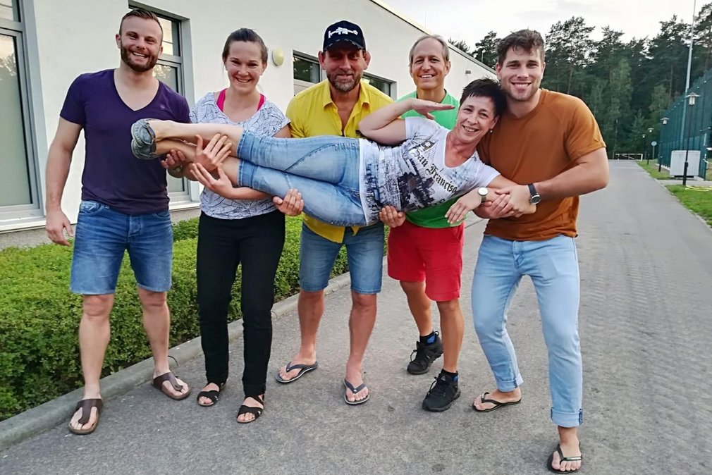 Gruppenfoto von mehreren Personen, die laechelnd fuer die Kamera posieren.