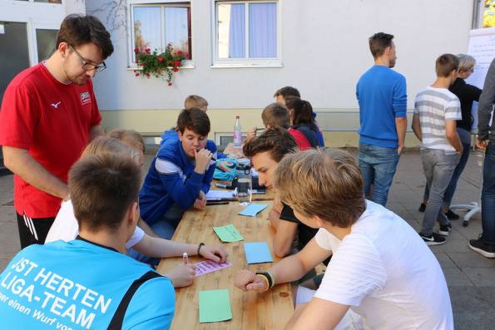 Eine Gruppe junger Menschen schreibt etwas auf Karteikarten.