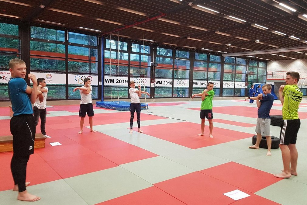 Einige Jungs waermen sich vor dem Training auf, stehen im Kreis und mobilisieren ihre Schultern.