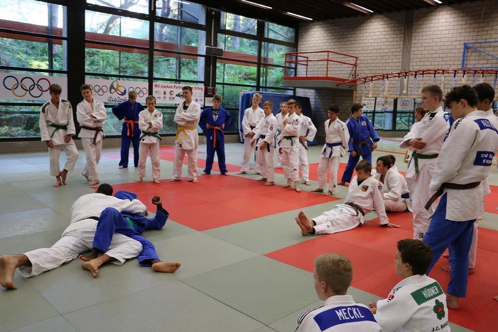 Zwei Judoka bei einem Trainingskampf im Power Boys Camp. Alle anderen stehen im Kreis drum herum und schauen zu.