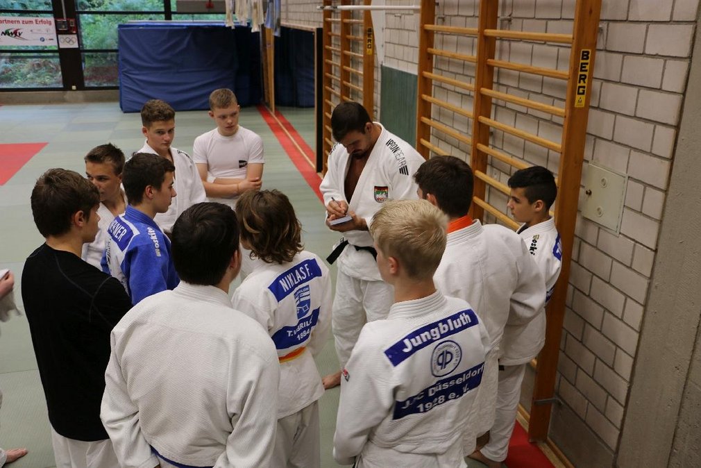 Einige Judoka stehen im Kreis um ihren Trainer beim Training im Power Boys Camp.