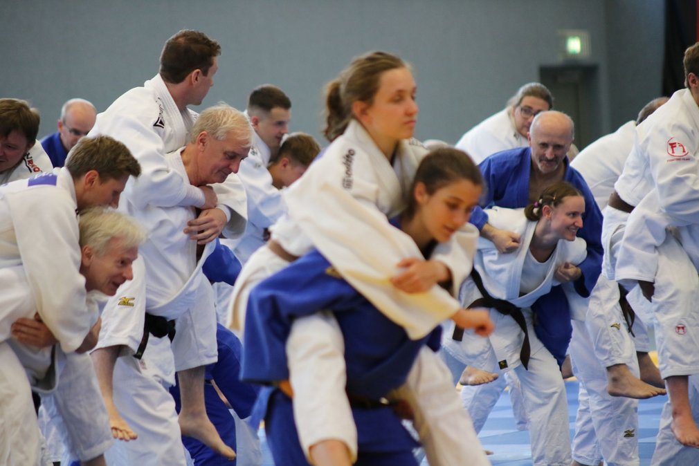 Momentaufnahme bei einem Training. Die Teilnehmenden tragen sich gegenseitig auf dem Ruecken.