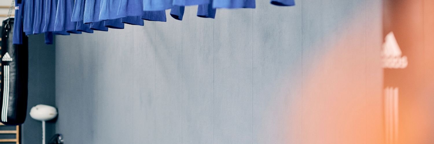 Eine Detailaufnahme einer Sporthalle, mit blauen Guerteln und einem Boxsack.