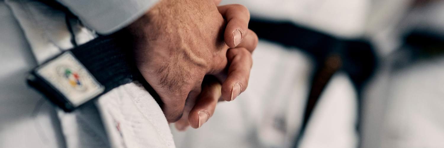 Detailaufname der Haende eines Judoka mit schwarzem Guertel.
