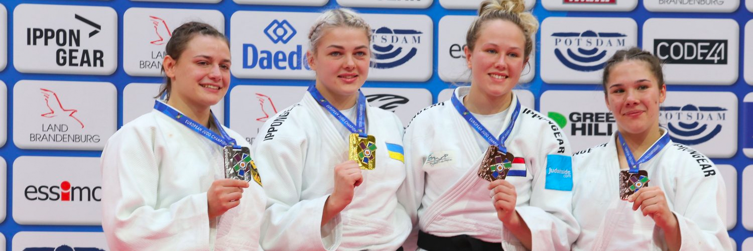 Vier Judoka halten ihre Medaillen in die Kamera.