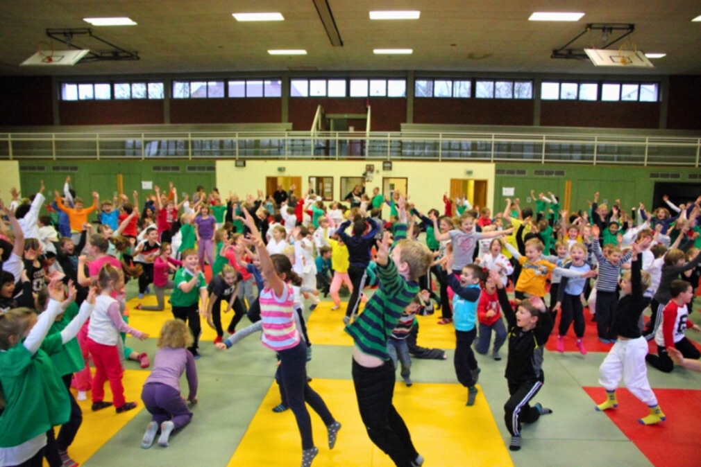 Kinder, die in einer Turnhalle springen und jubeln.