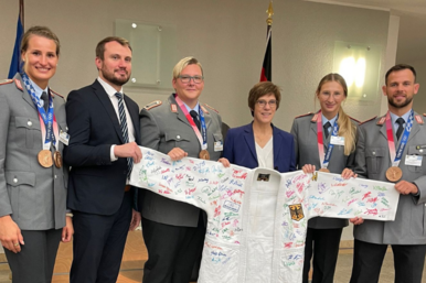 Einige Personen posieren mit einem Judoanzug der Deutschen Nationalmannschaft auf dem viele Unterschriften stehen.