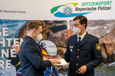 Ein Absolvent der Polizei bekommt sein Zeugnis ueberreicht.